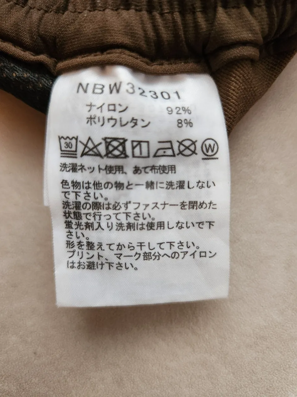 アルパインライトパンツの品質表示。NBW32301、ナイロン92%・ポリウレタン8%、蛍光剤入り洗剤は使用しない