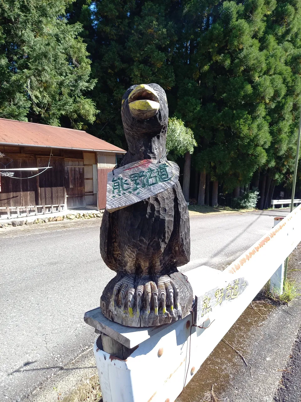 熊野古道の道ばたに立つ八咫烏の木彫り。胸の帯に「熊野古道」と彫ってある