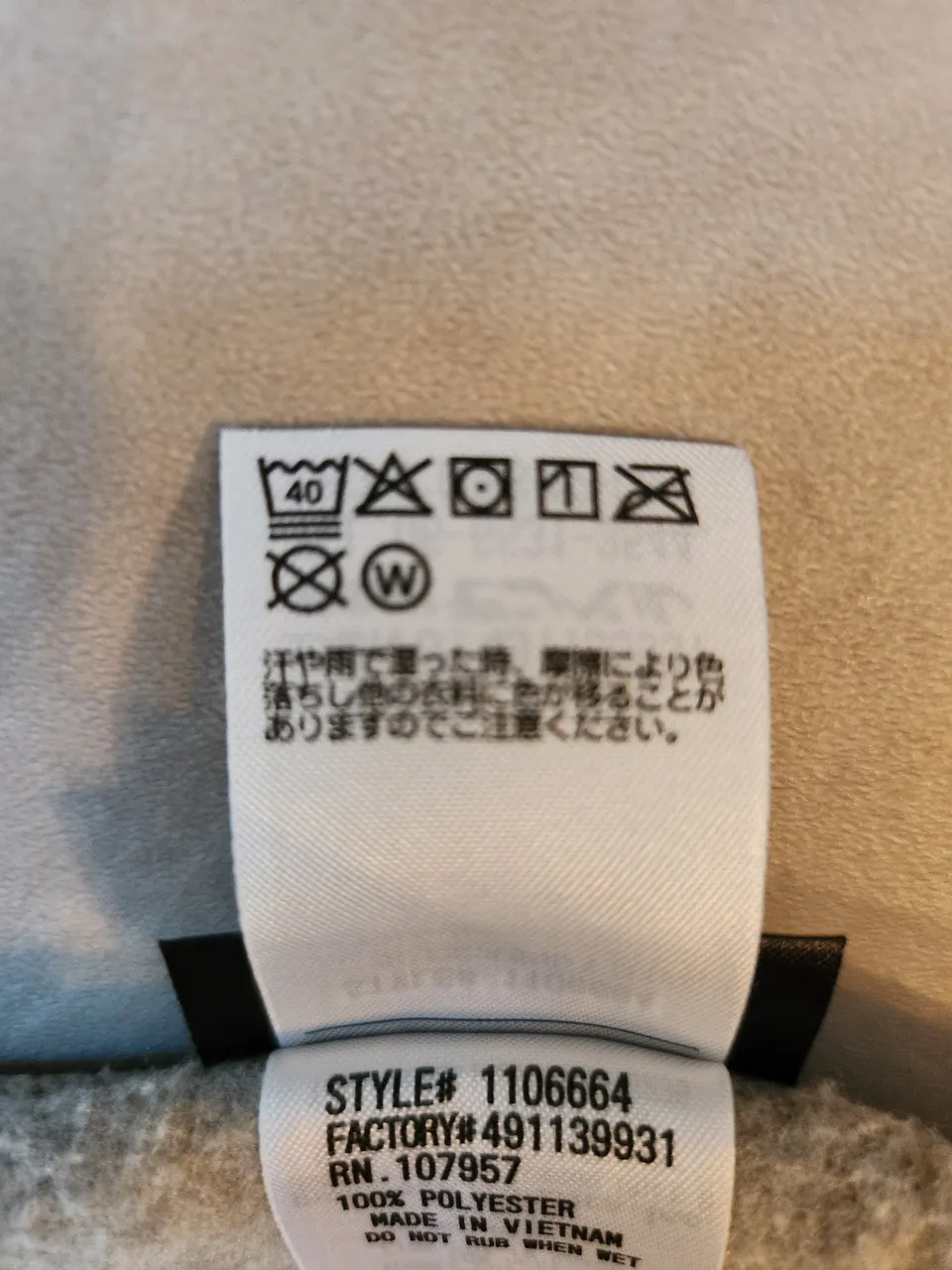 クリマプラスニットカーディガンの洗濯表示。洗濯機40℃・漂白剤不可・つり干し・アイロン不可・ドライクリーニング不可、湿ったときの色移りの注意